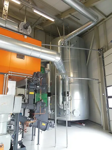 Biomasseheizzentrale (orange) und Pufferspeicher (grau metallic)